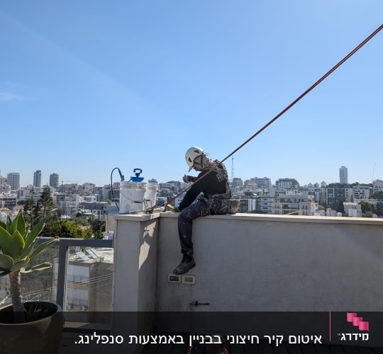 אדם עם קסדה יושב על גג עם ציוד עבודה